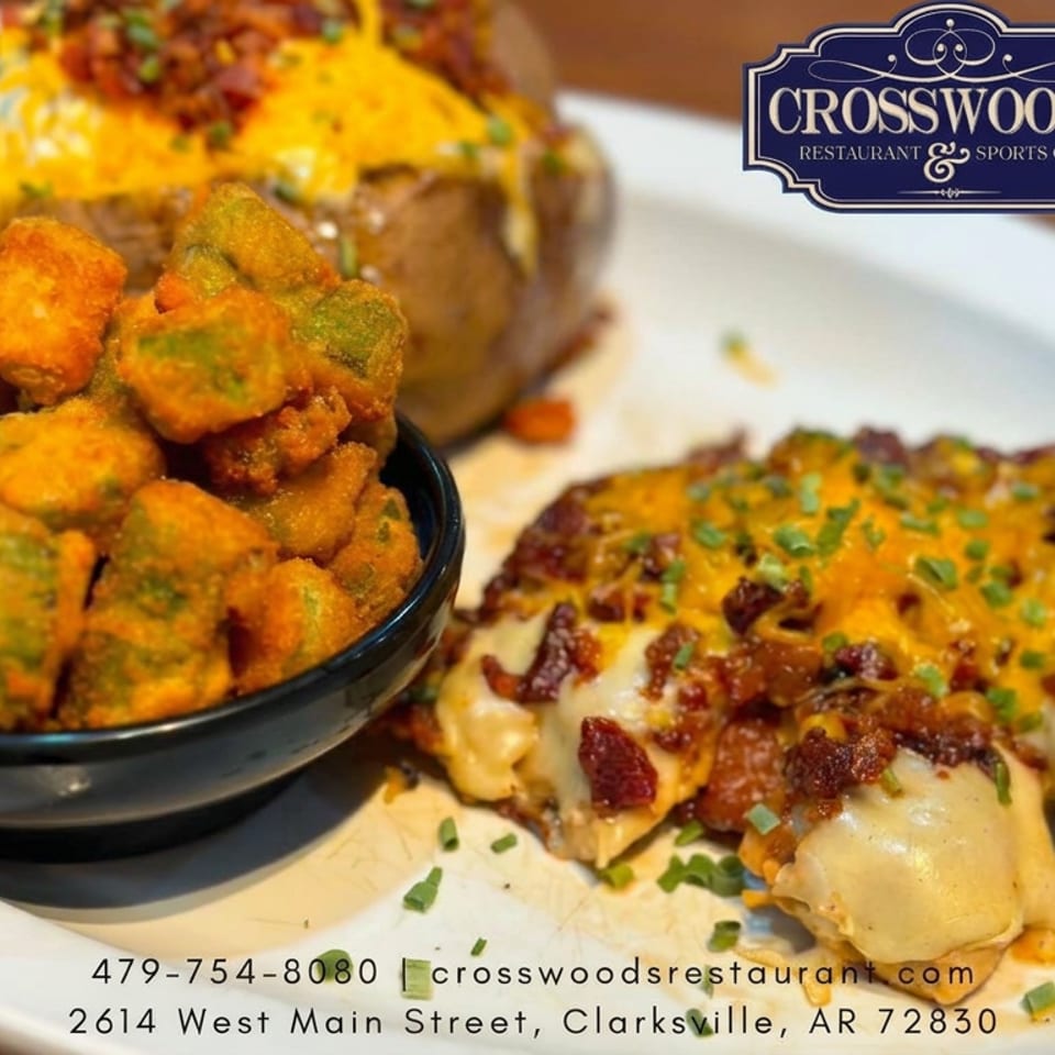 Loaded cheesy chicken entrée with bacon and chives, fried okra, and a baked potato on a plate at Crosswoods Restaurant.